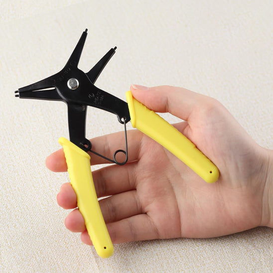 pince circlips poignees jaunes posee dans main
